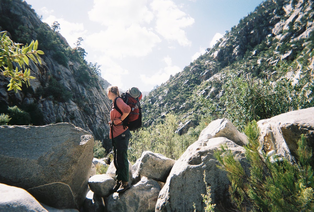 NOLS  student stands on boulders while hiking in Baja California