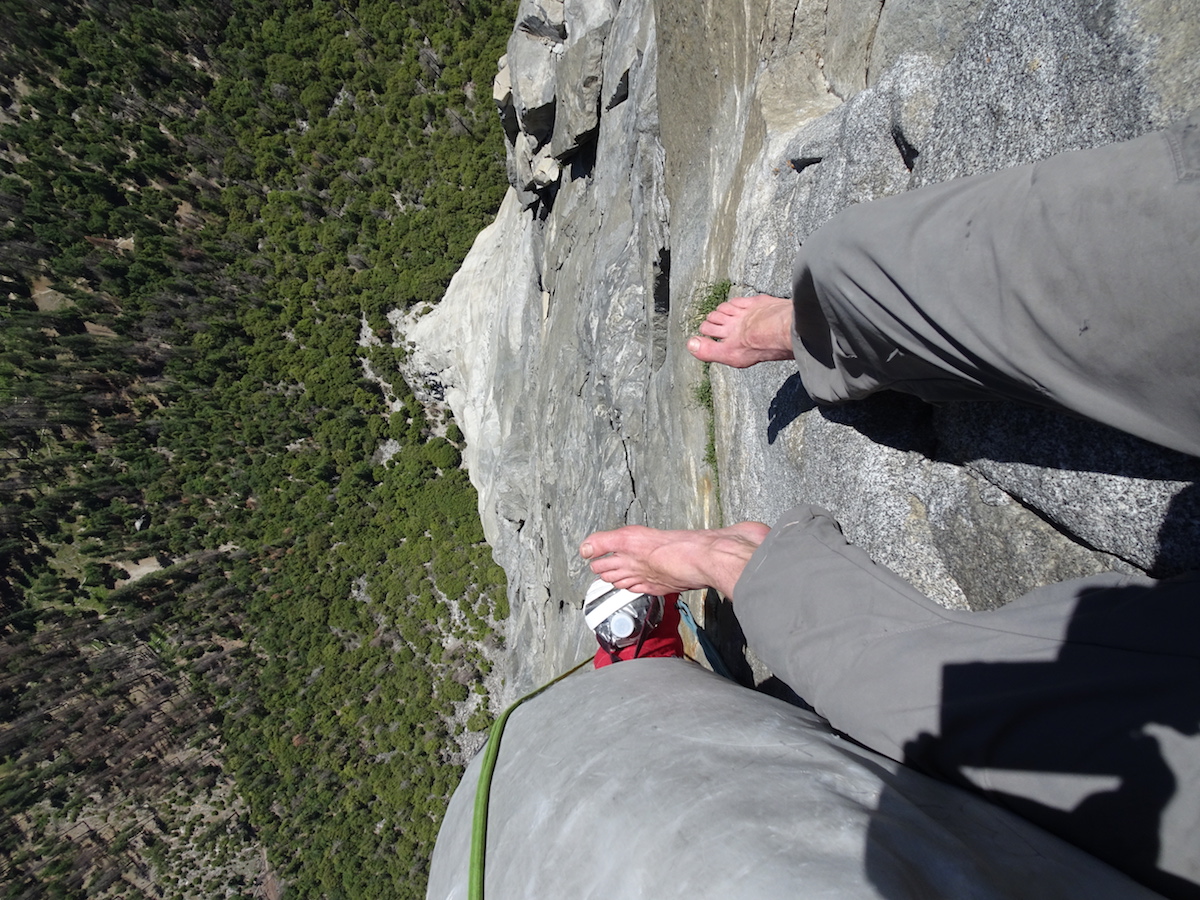 looking down on feet over a tall cliff