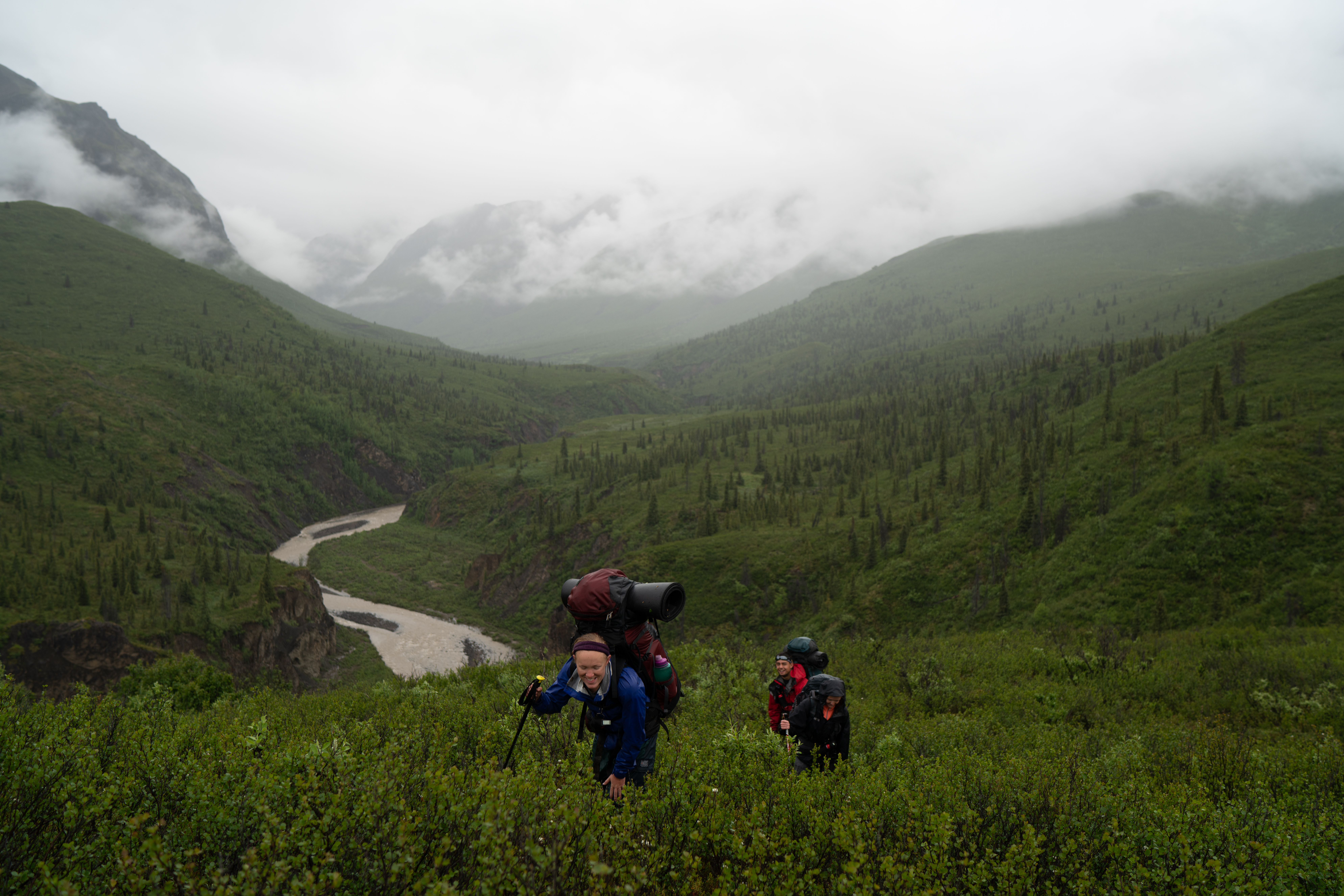Students hike up a ravine in the rain on an Alaska course