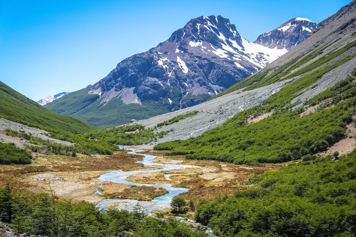 Patagonia landscape with mountains and river valley and very small distant tents