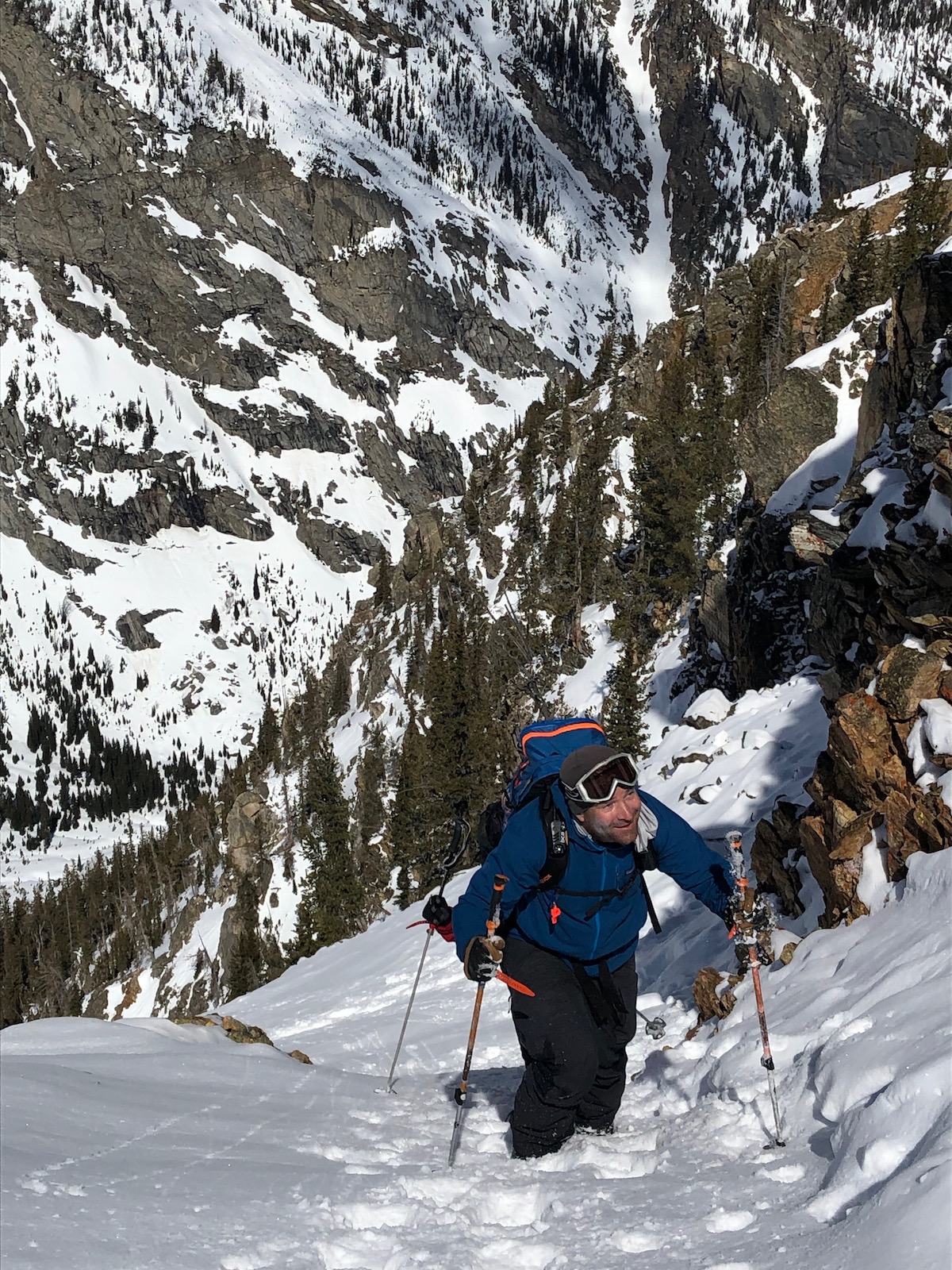 Person walking uphill in ski boots and smiling