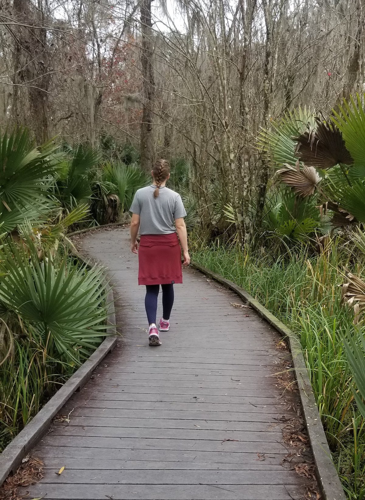 hiker walks along a boardwalk with palmettos on either side