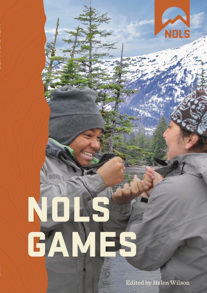 cover of NOLS games book smiling students playing game in the mountains