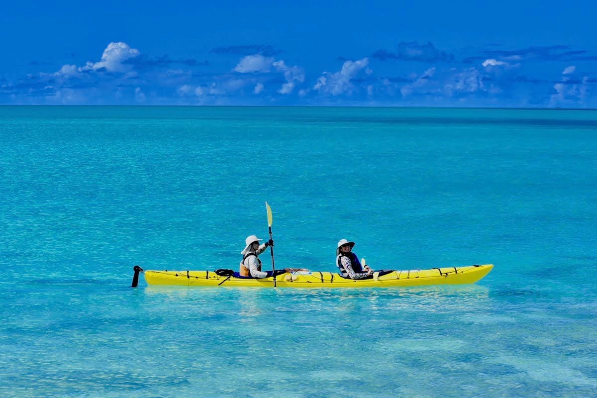 NOLS participants paddle a yellow double kayak in turquoise water in Baja