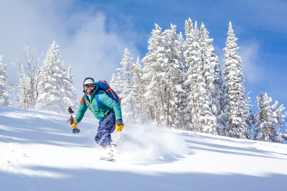 smiling NOLS participant splitboarding in fresh snow in the Rockies