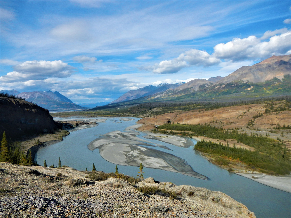 looking down on braided river with mountains and clouds in the distance