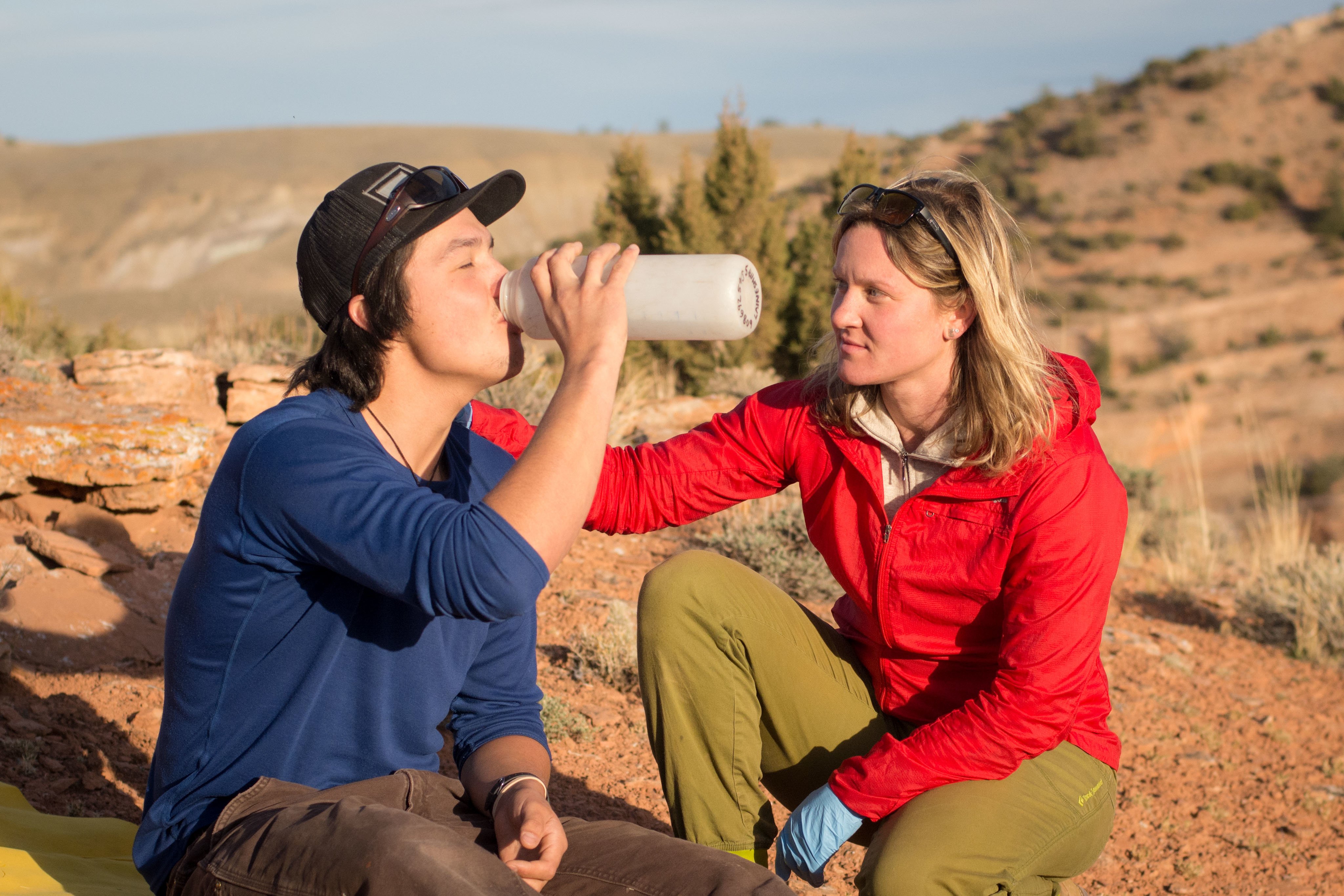 Person drinks from a water bottle with help from a first responder