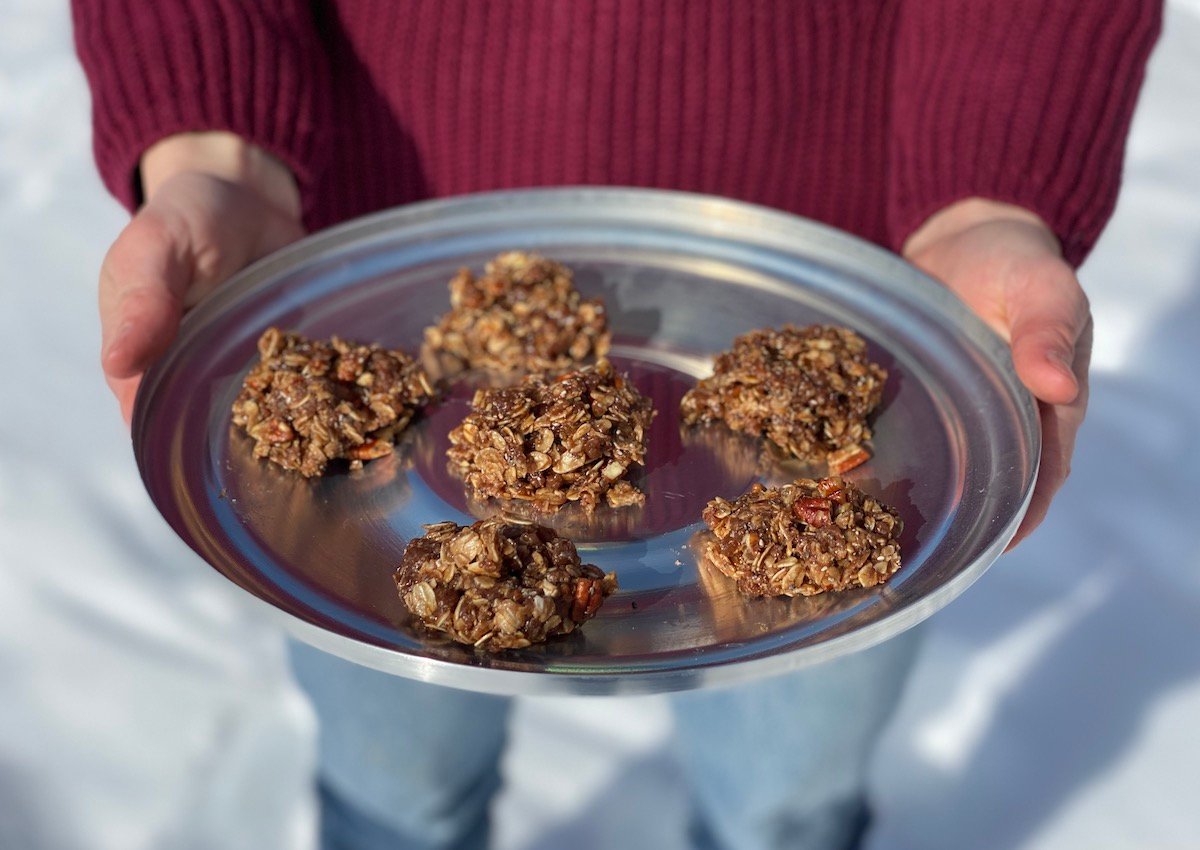 hands holding six fudge no-bake cookies on a tin lid