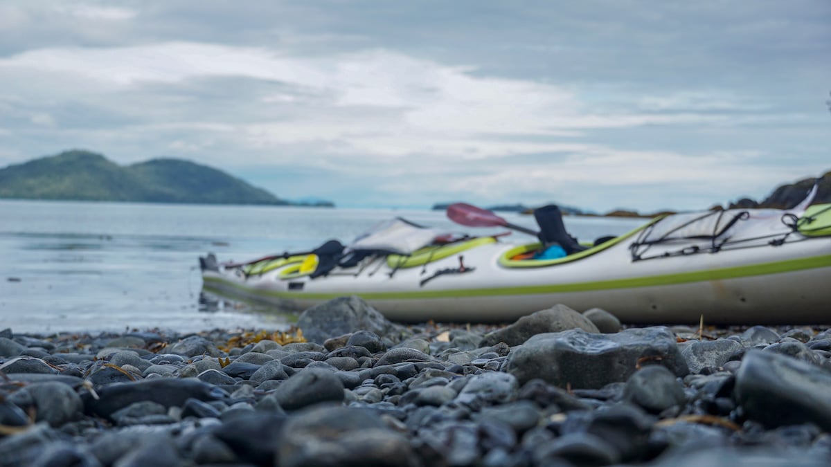 white and green sea kayak beached on a rocky shore in Alaska