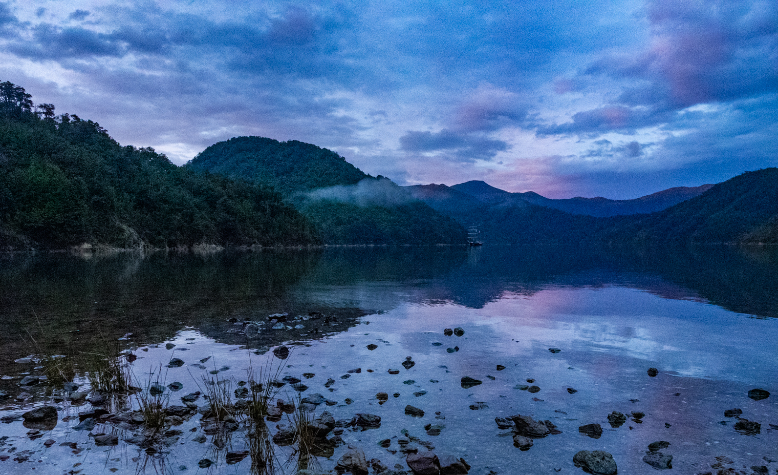 pink and purple sunset with wisps over cloud over calm water in New Zealand