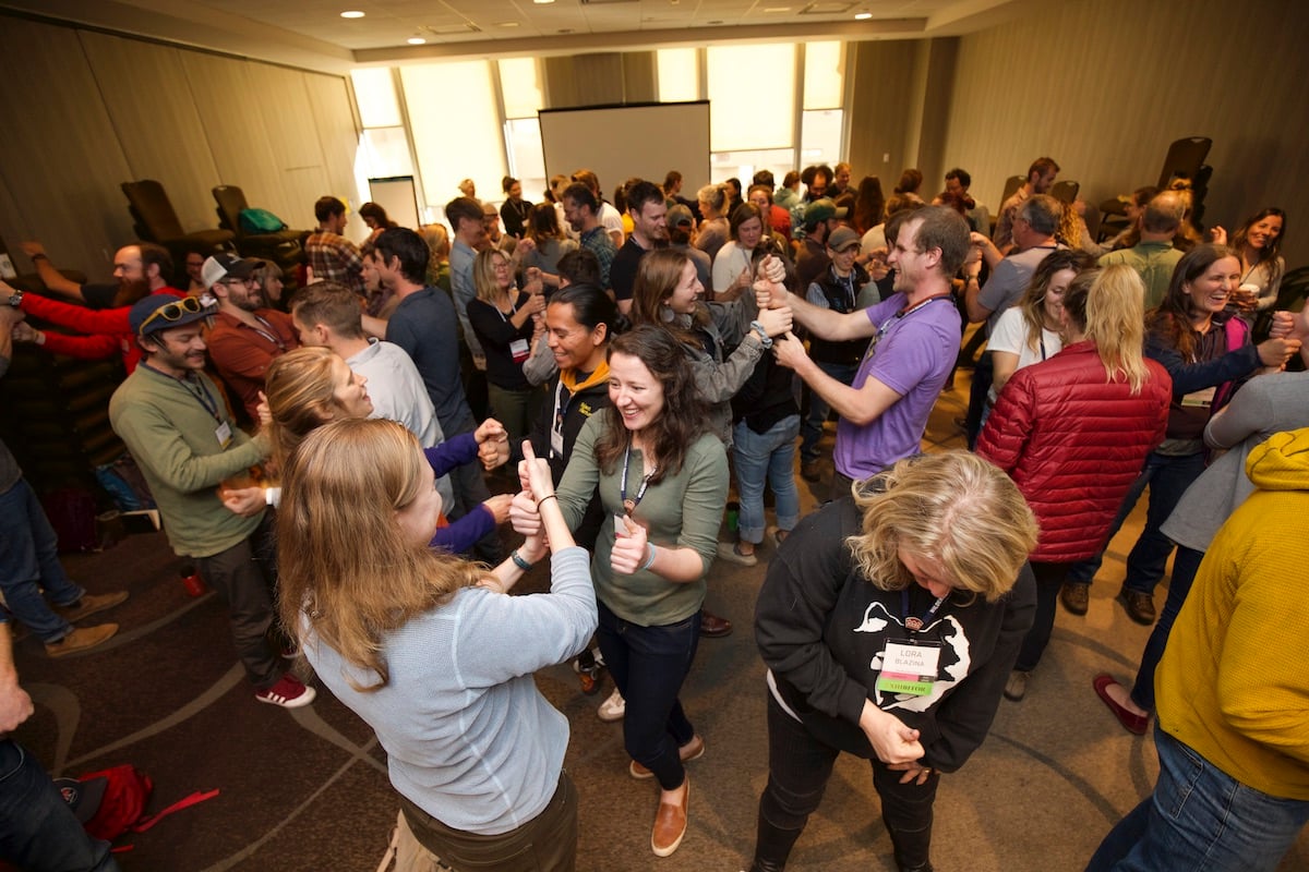 smiling WRMC attendees in a crowded room stand to participate in a group activity