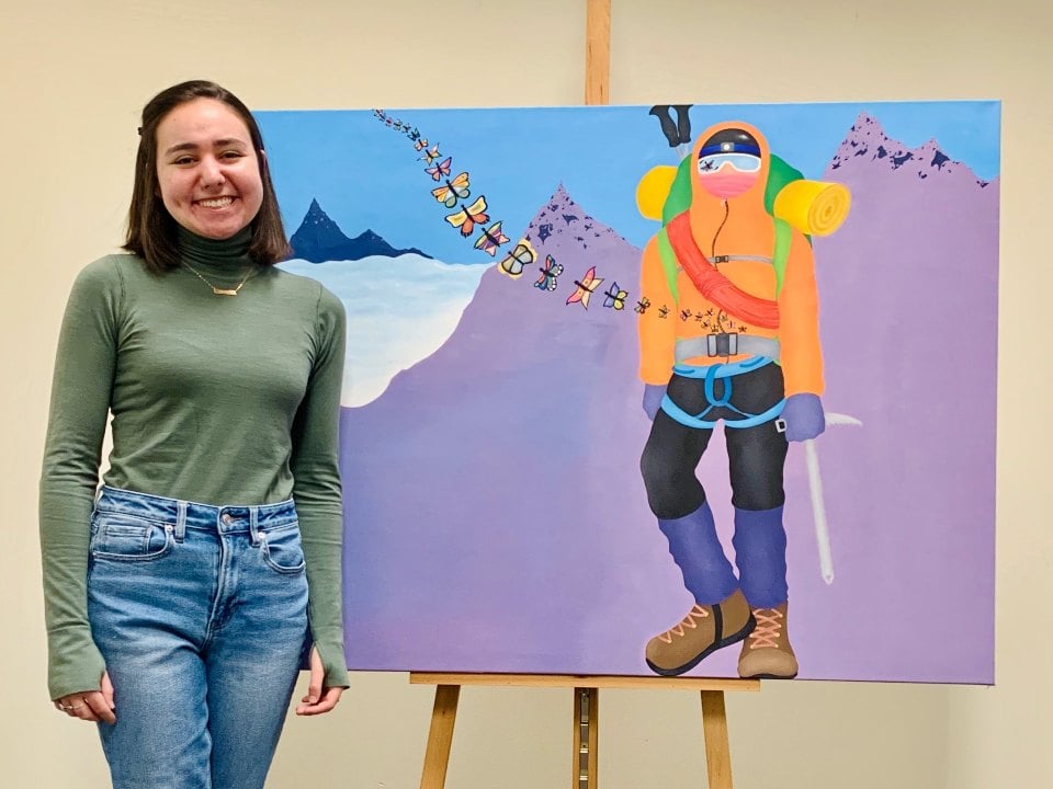 Artist Dori smiles next to one of her paintings
