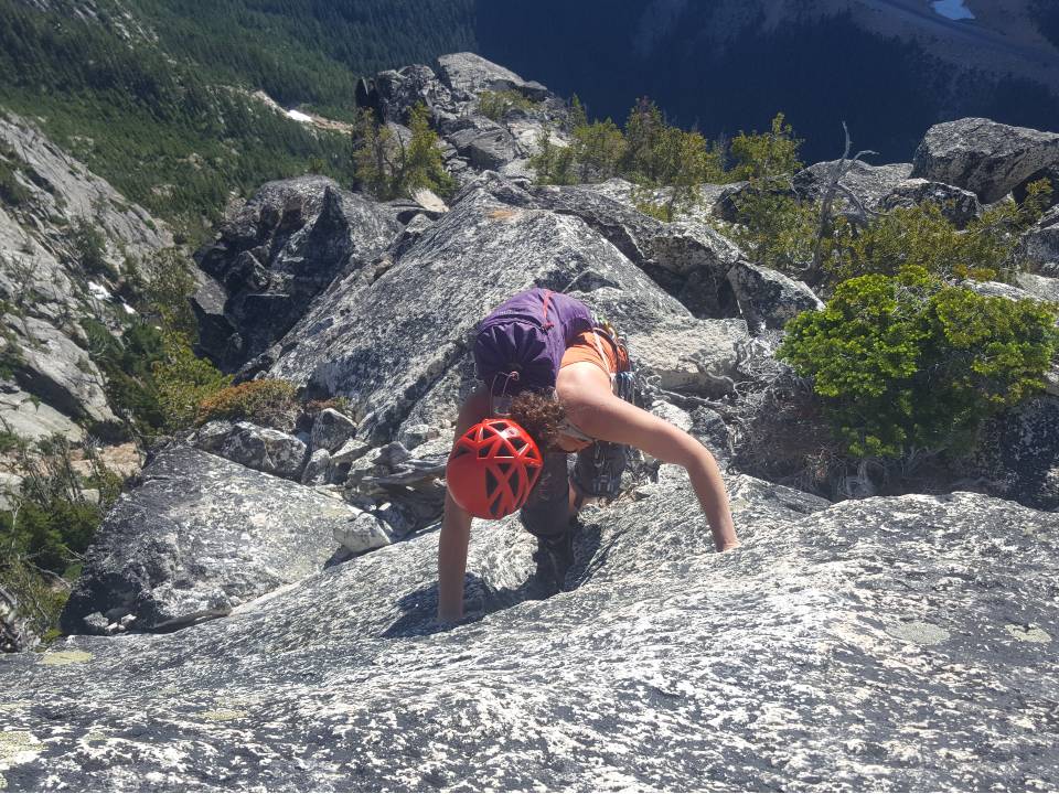 Climber looks down at her feet while ascending a slab