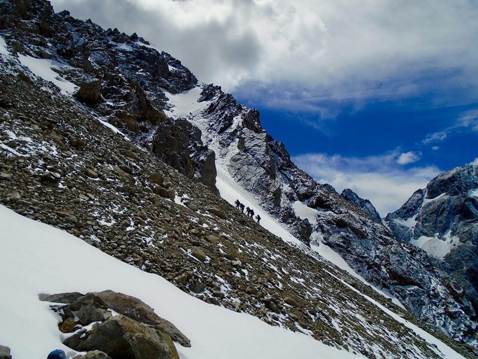 Small group hikes uphill in snowy mountains