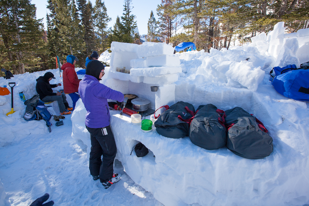 A snow kitchen with shelves, benches, a "stove," and an icebox