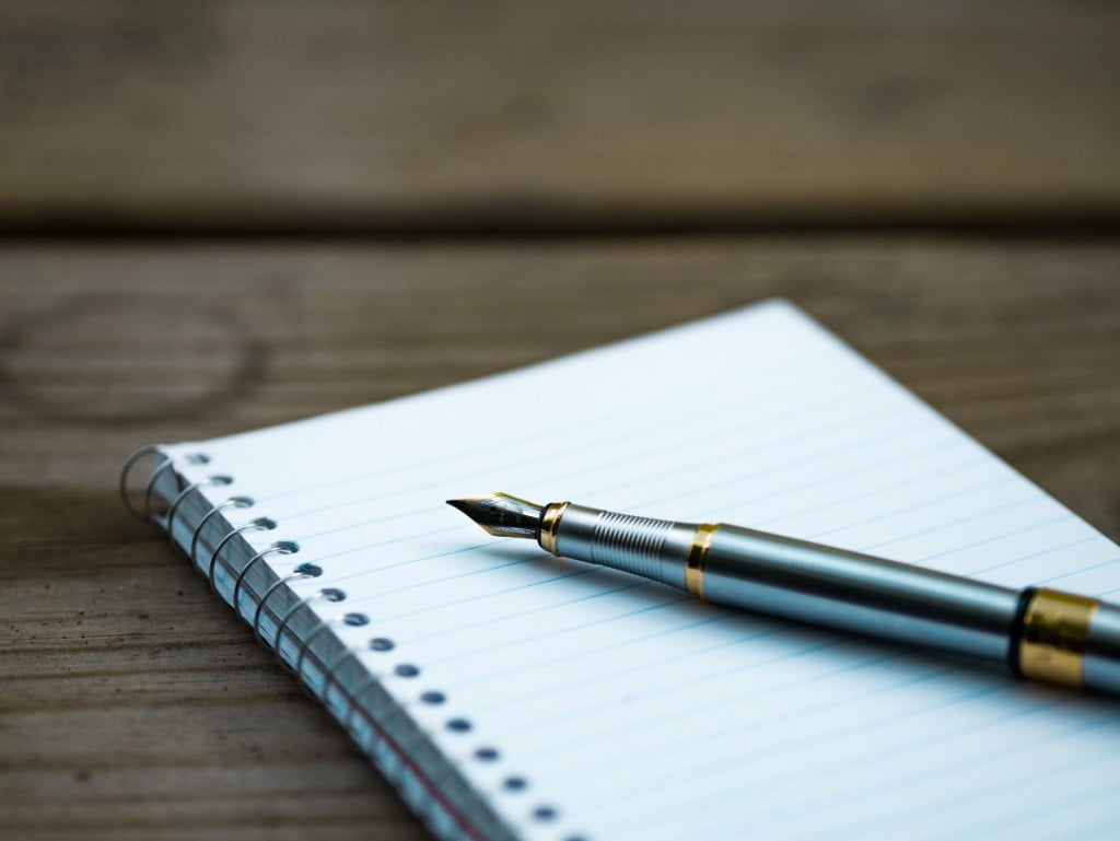 Fountain pen resting on a blank notebook