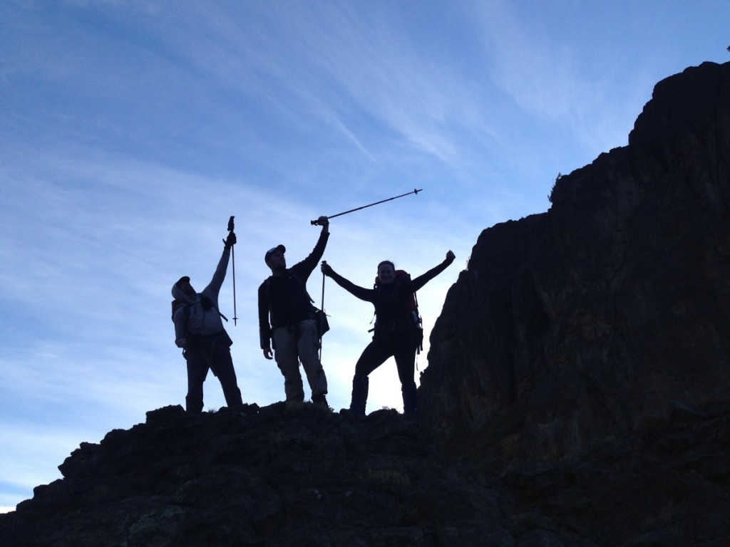 Three backpackers silhouetted on a ridge