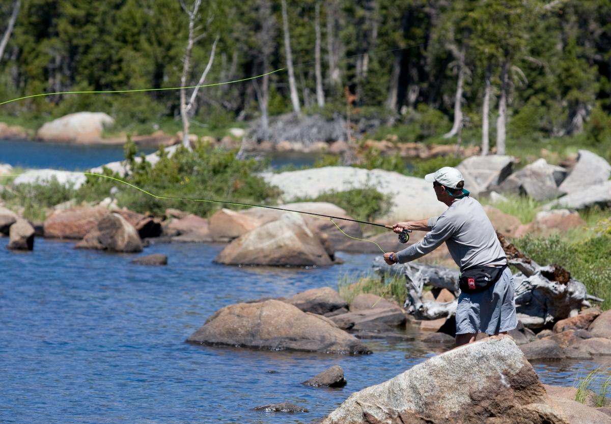 Person casting while fly fishing on a river