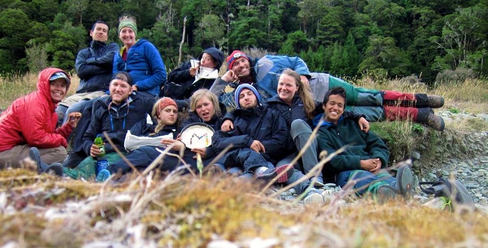 NOLS students gather for a photo with a birthday cake made on a camp stove