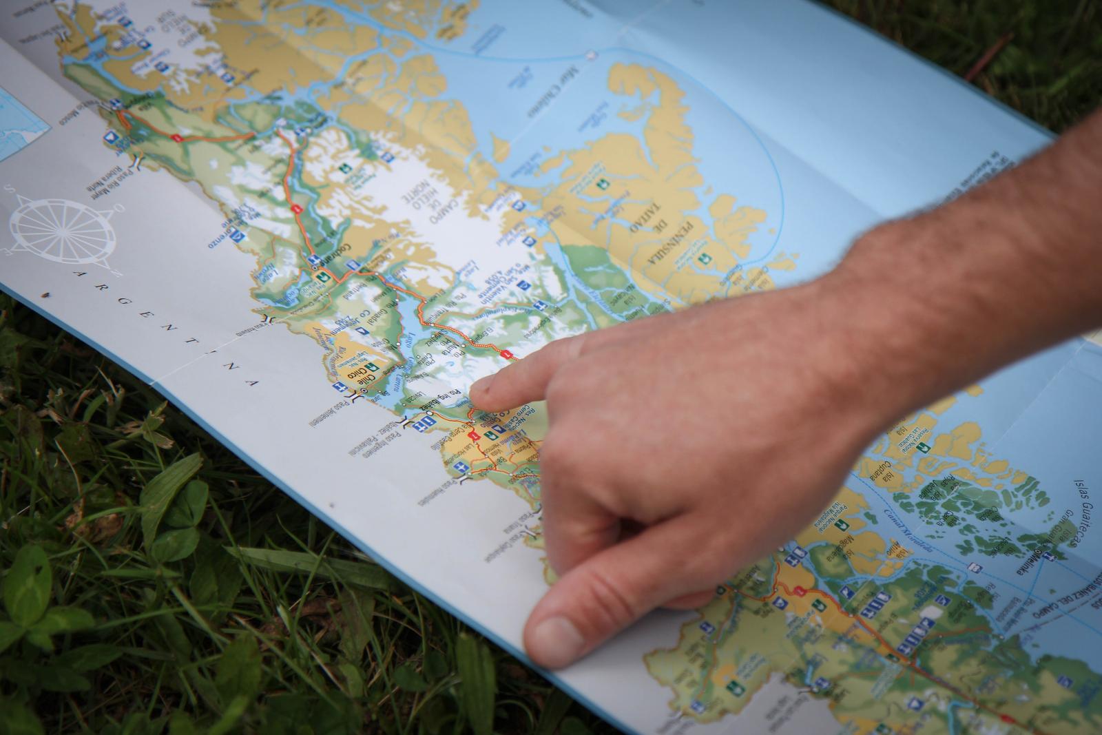 hand pointing to a destination on a map laid on the ground
