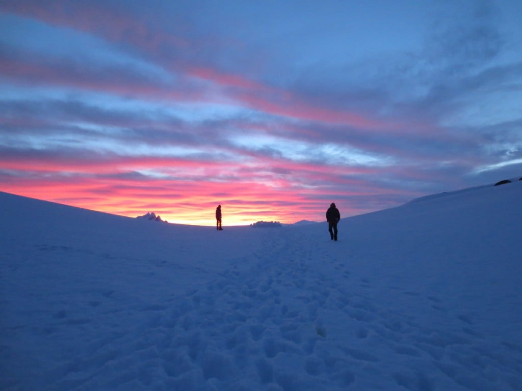Mountaineers climb a slope at sunrise