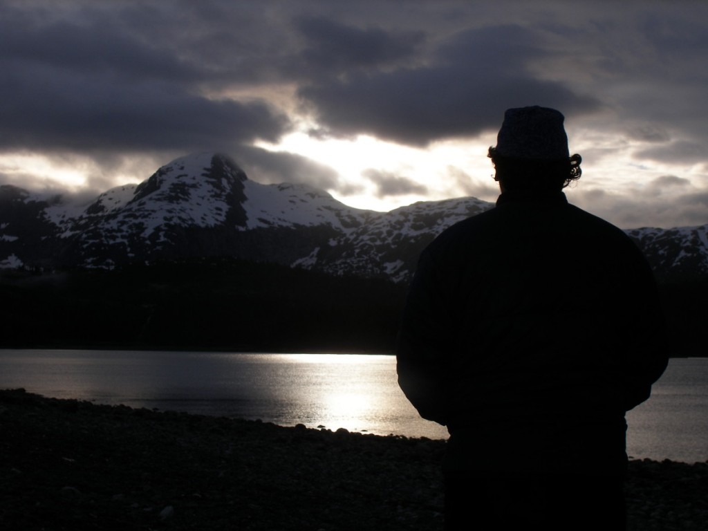 silhouetted figure faces snow-covered mountains