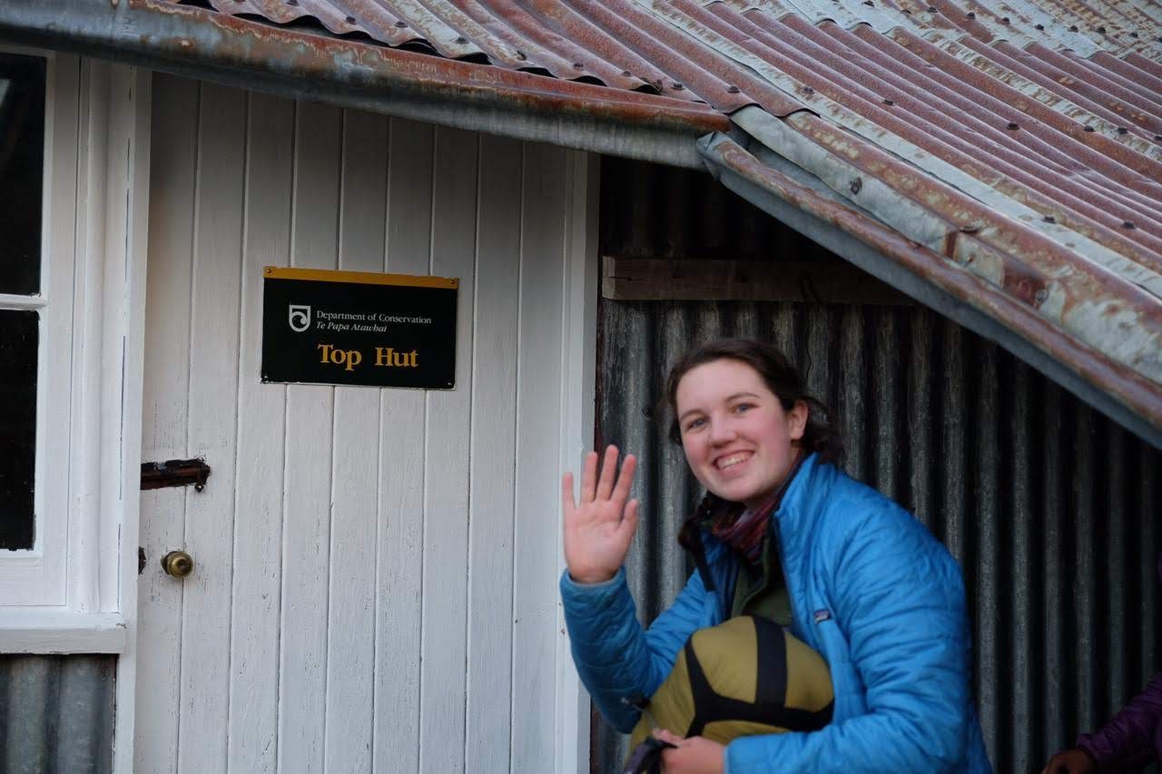 Tricia Ballard waves outside a hut in New Zealand