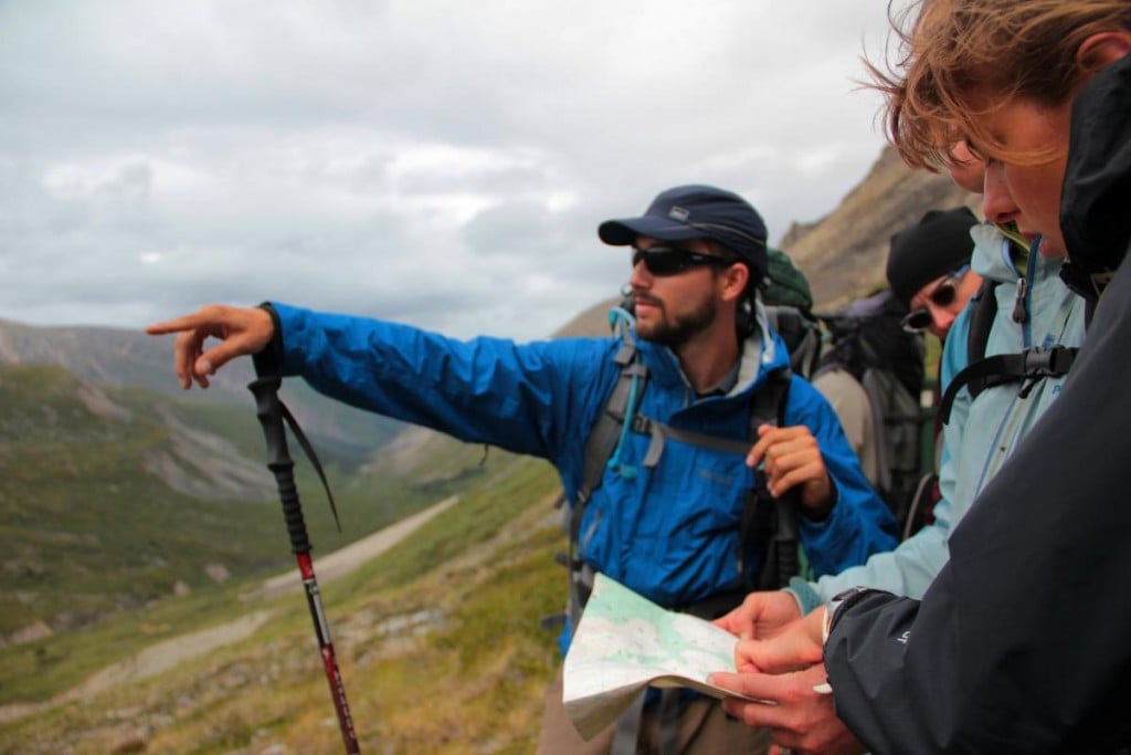 Person backpacking in a group pointing in the distance